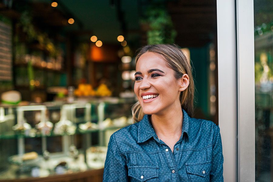 Business Insurance - Portrait of Smiling Small Business Owner Standing in Front of Her Store